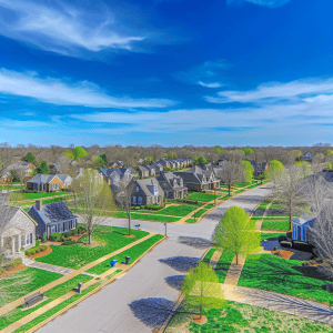 Aerial view of a suburban neighborhood with manicured lawns and clear skies.